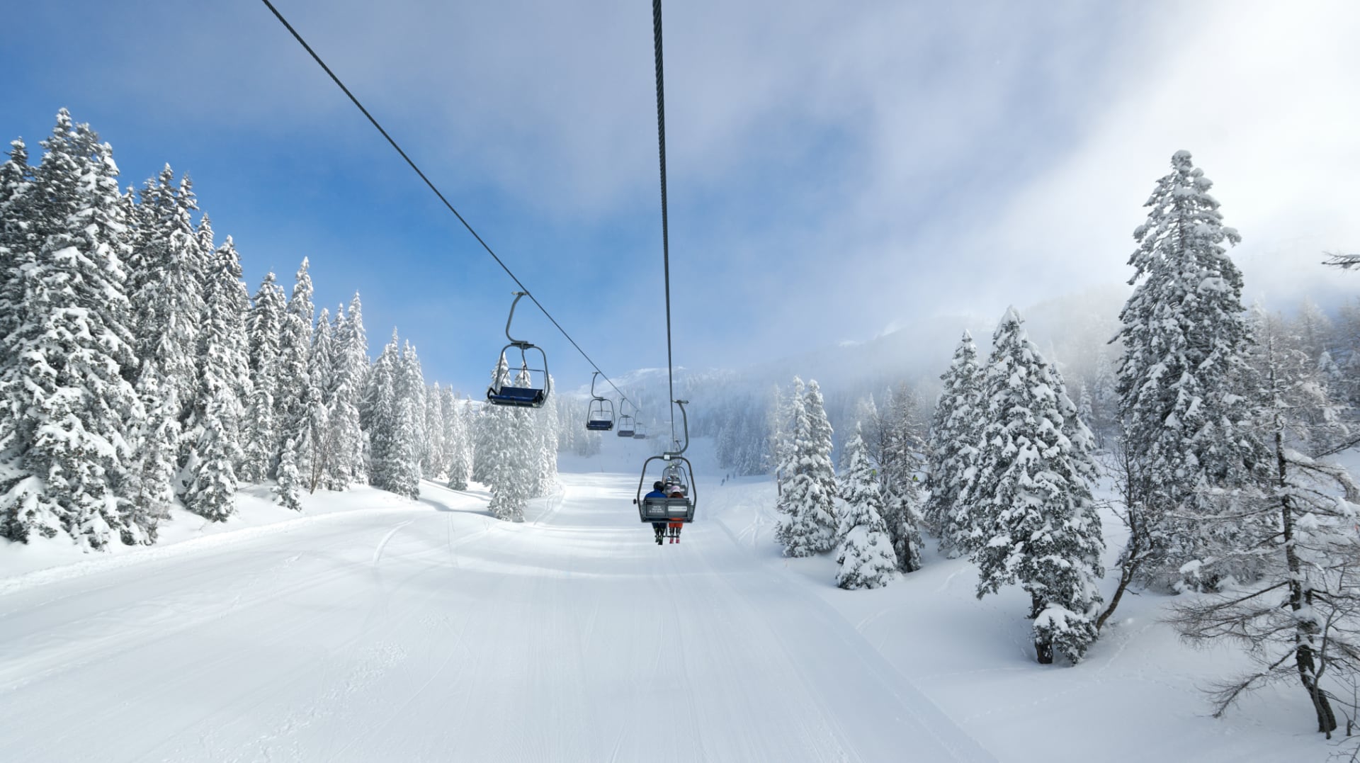 A chairlift through snow-covered forest at Krvavec